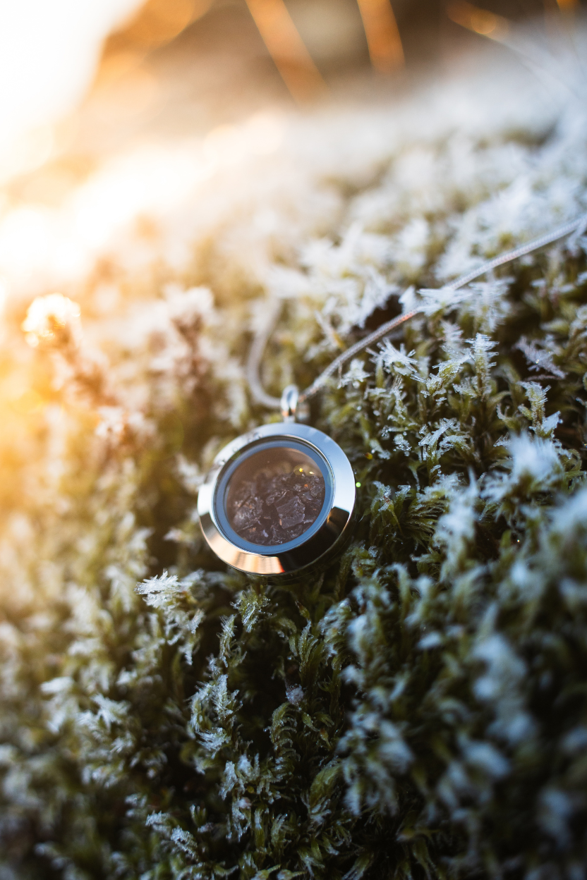 Dragon Glass necklace with a locket containing real obsidian lying on Icelandic moss.
