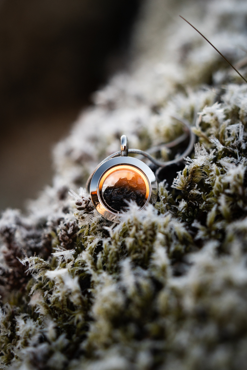 Dragon Glass necklace with a locket containing real obsidian lying on Icelandic moss.
