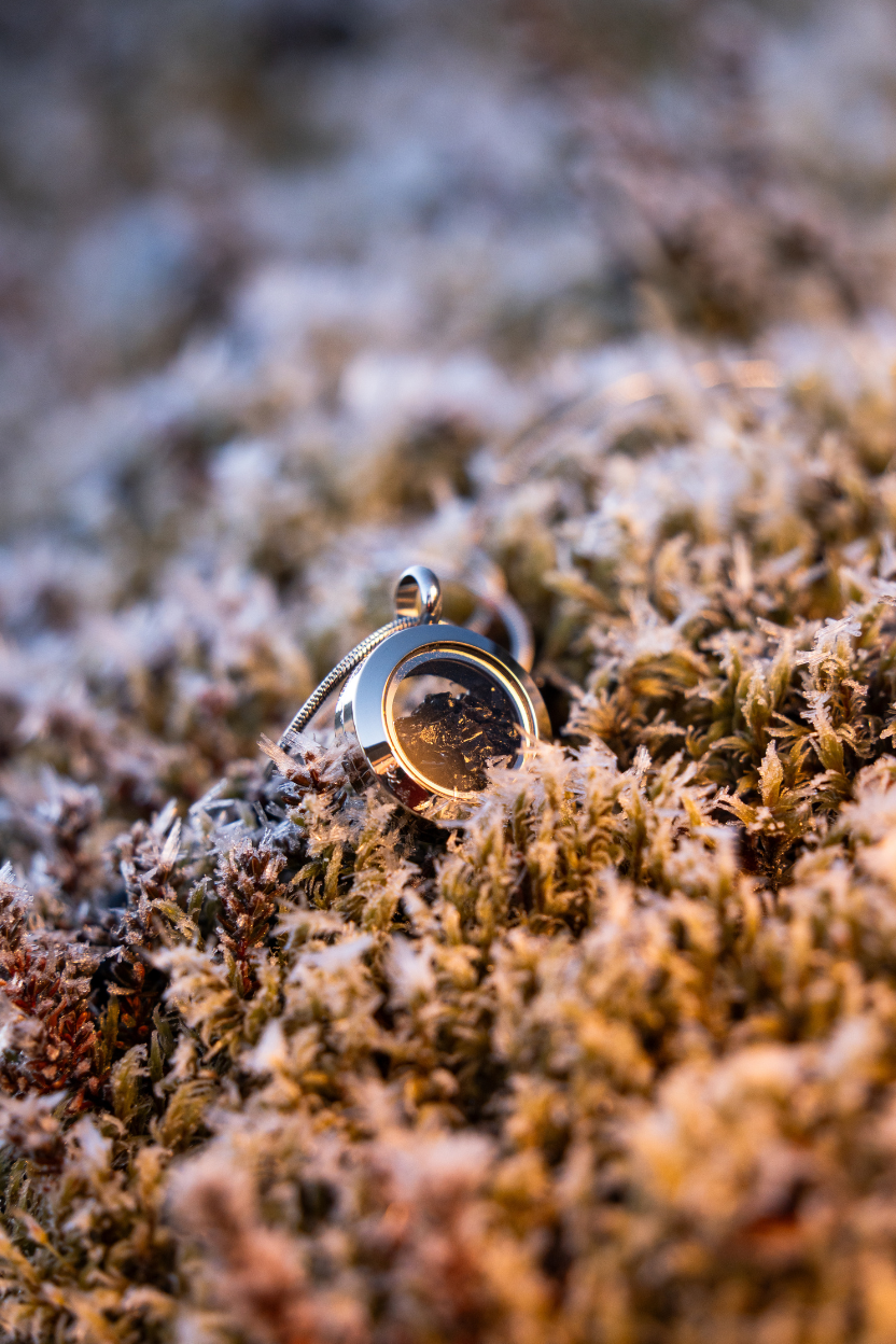 Dragon Glass necklace with a locket containing real obsidian lying on Icelandic moss.
