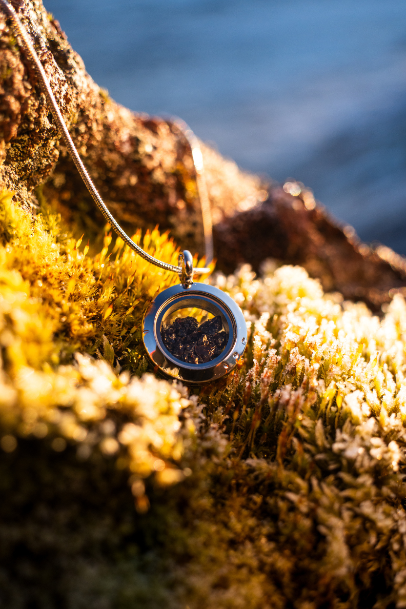 Dragon Glass necklace with a locket containing real obsidian lying on Icelandic moss.
