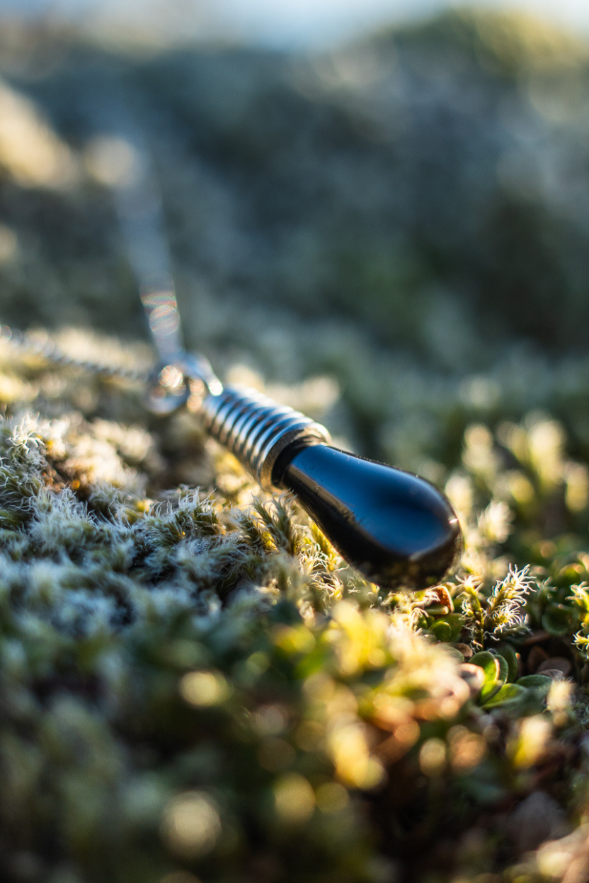 Pele's Tear sterling silver necklace with no swirl lying in green 
Icelandic moss. 