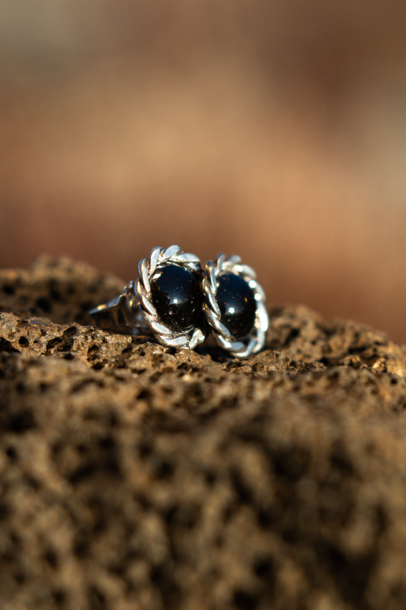 Pele’s Tear from Lava Show – Sterling silver stud earrings with black lava stones on a textured brown surface
