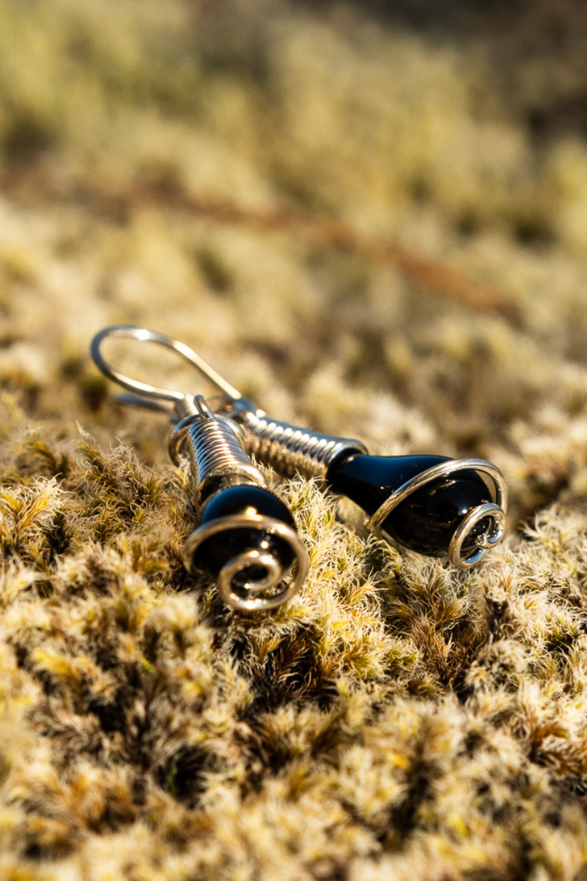 Pele's Tear's sterling silver earrings with swirl lying in Icelandic moss.
